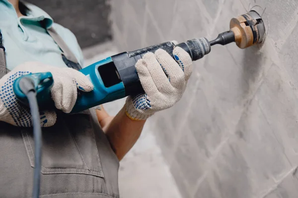 Constructor hombre cortando persecución eléctrica en la pared de hormigón con taladro de martillo corona de diamantes — Foto de Stock