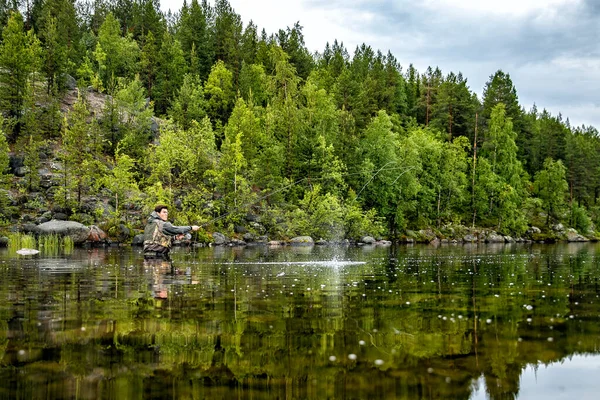 Fliegenfischer fängt Lachsfisch, der Wasser spritzt — Stockfoto