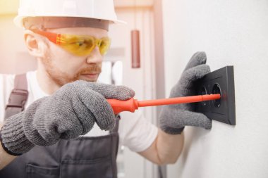 Elektrikçi inşaatçısı çalışan anahtar ve soketleri tornavida aracı yükle