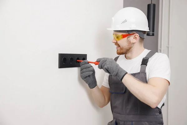 Electrician builder working switches and sockets of residential electrical system, black color