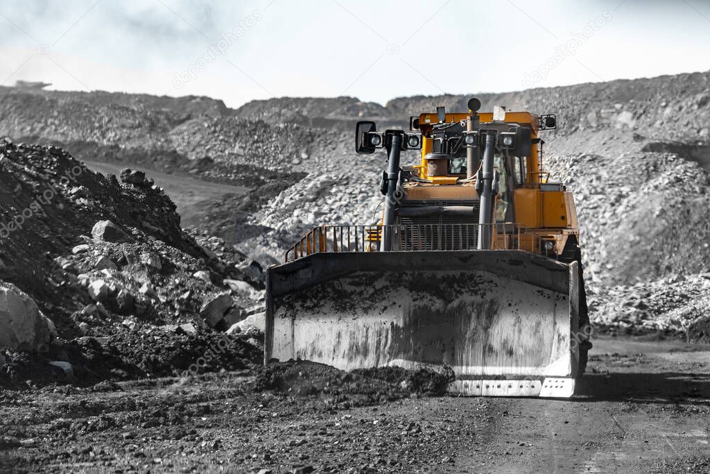 Bulldozer levels road with grader after coal explosion. Open pit mine industry