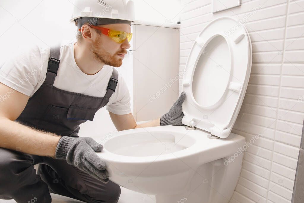 Plumber installing toilet bowl in restroom, work in bathroom