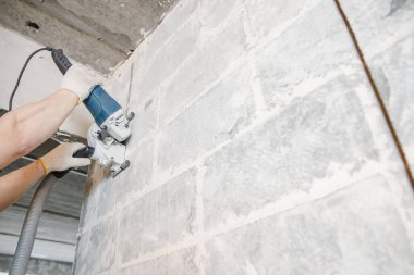 İnşaat işçisi beton duvardaki elektrikli kovalamacayı kesiyor.