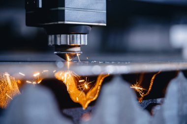 CNC gazı metal levha kesiyor, kıvılcımlar uçuşuyor. Mavi çelik rengi, modern endüstriyel teknoloji.