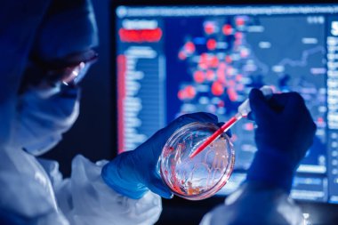 Eczane laboratuarında 2019 ncov Coronavirus aşısı üzerinde çalışan tıbbi biyomühendis. Mavi renk arkaplan