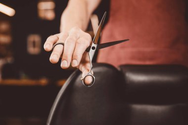 Yakın plan berber, klipsli saç makasıyla berber dükkanı işletiyor.