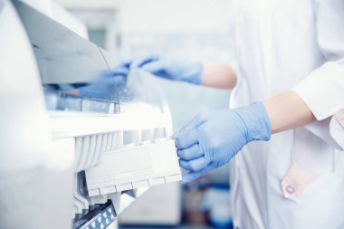 Biyomühendis DNA analizi için otomatik test cihazına kan plazması örneği yükler ve antibiyotiklere ve alerjilere karşı tepkileri kontrol eder.