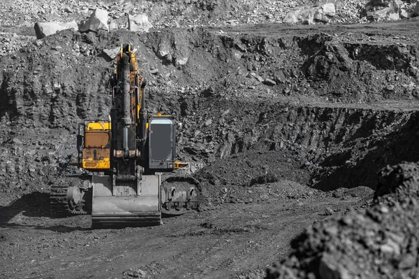Żółty koparka działa i wydobywa węgiel z jelit ziemi. Przemysł kopalń odkrywkowych — Zdjęcie stockowe