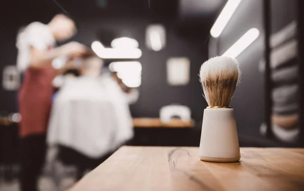 Кисть для бритья бороды вдоль, размытый фон парикмахерской для мужчин, парикмахерская — стоковое фото