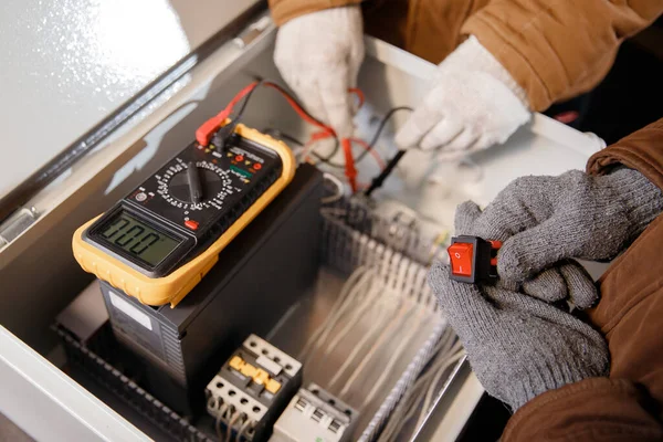 Master electrician checks electrical panel with multimeter for short circuit — Stock Photo, Image