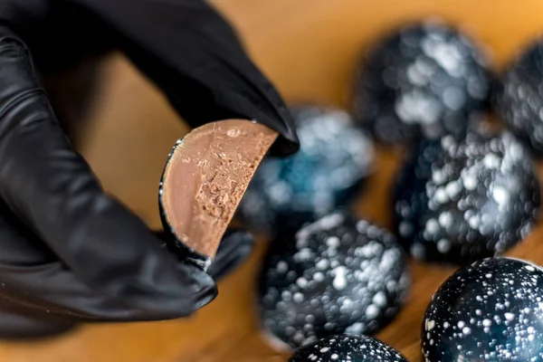 Il pasticcere tiene la caramella di cioccolato belga, il riempimento di caramelle è mostrato — Foto Stock