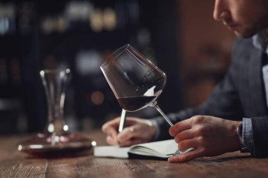 Sommelier erkekleri bardakta şarap tadımı ve degukasyon kartı tutarlar.