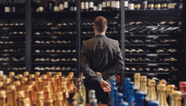 Cantinero sommelier recoge botella de vino de estante en el restaurante con exquisitas bebidas — Foto de Stock