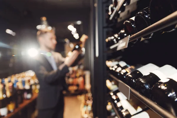 Cantinero sommelier toma botella de vino tinto del mostrador de la tienda de bebidas restaurante — Foto de Stock