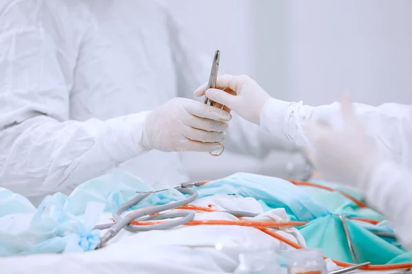 Nurse hands surgeon blood clip on operating table