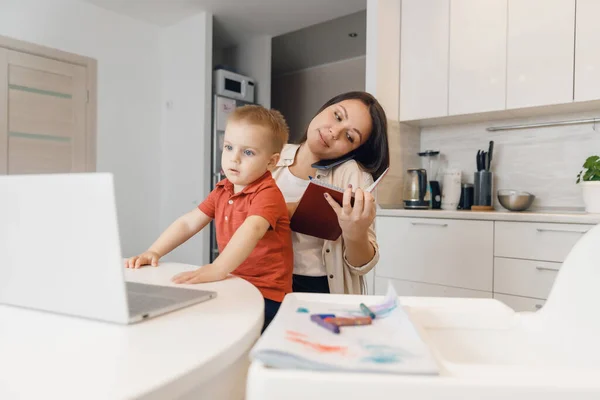 Businesswoman mother woman with small child son working online computer home office