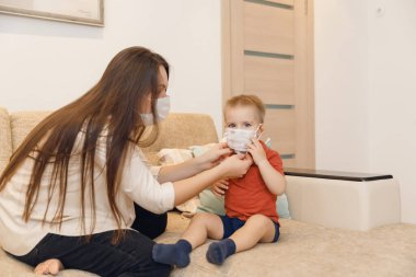 Anne ve çocuk, koronavirüs sırasında halka açık yerlerde yürümek için tıbbi maske takıyor. Koruyucu virüsü ve hastalığı kabul et