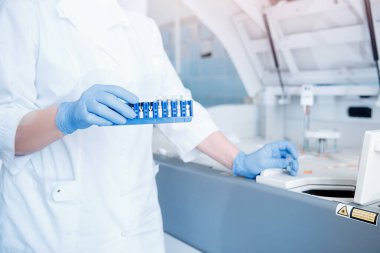 Biyomühendis DNA analizi için otomatik test cihazına kan plazması örneği yükler ve antibiyotiklere ve alerjilere karşı tepkileri kontrol eder.