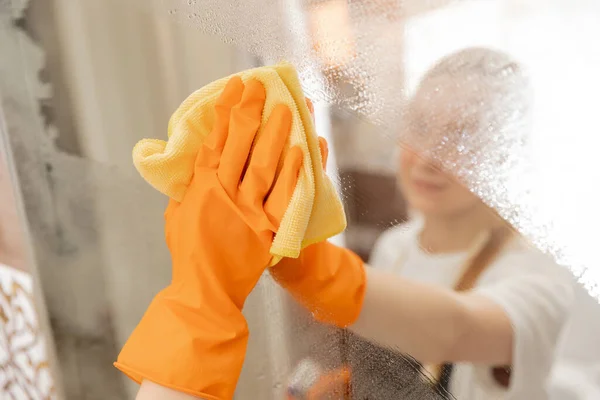 Женщина очищает зеркало от загрязнения и налет от воды в ванной комнате — стоковое фото