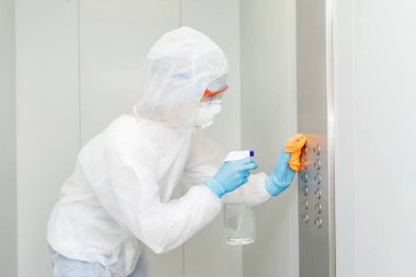Coronavirüs dezenfeksiyonu. Tehlikeli maddeler kullanan insanlar asansör dairesinde temizlik yapıyorlar.