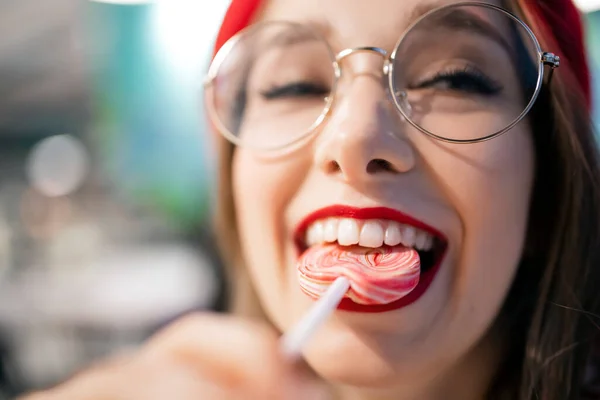 Chica joven comiendo palo pegajoso dulce en Francia café en boina roja y vasos. Concepto de caries y el daño es peligro para el esmalte dental — Foto de Stock
