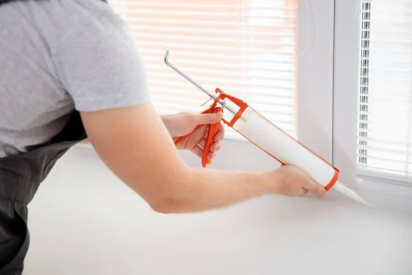 Bouwvakker gebruik pistool siliconen buis voor het repareren en installeren van raam in huis — Stockfoto
