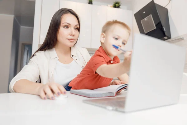 Beautiful woman helps son learn how to write alphabet letters. Online learning concept