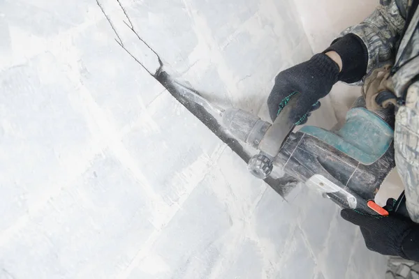 Constructor trabajador hombre utilizando martillo neumático para perforar en la pared de construcción para conducto para tubos de aire acondicionado — Foto de Stock