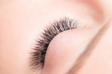 Güzellik salonunda kirpik uzatma prosedürü. Makro. Makyajlı güzel göz, üst manzara.