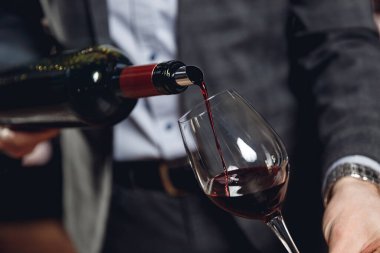 Sommelier adam bardağa su sıçratmadan kırmızı şarap doldurur.