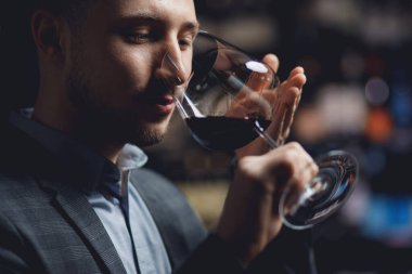Sommelier restoranda kırmızı şarapla bardağı tutuyor, aromayı ve rengi test ediyor.