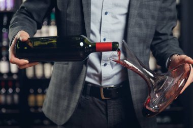 Sommelier erkeği tat ve aromanın havalanması için sürahiye kırmızı şarap doldurur.