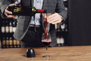 Sommelier şişenin içine kırmızı şarap koyuyor. Havalandırma içeceği yapmak için.