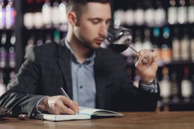 Sommelier erkekleri bardakta şarap tadımı ve degukasyon kartı tutarlar.