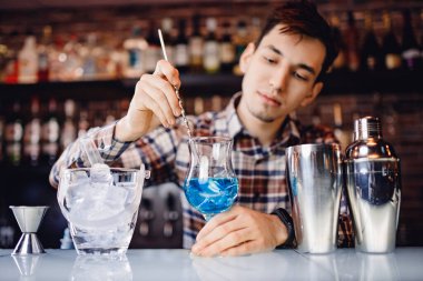 Barmen renkli alkollü kokteyl tezgahıyla kokteyl gösterisini karıştırıyor.