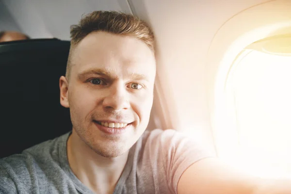 Gelukkig toerist maakt selfie foto in cabine vliegtuig voor vertrek. Reisconcept — Stockfoto