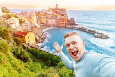 Tourist happy young man taking selfie photo Vernazza, national park Cinque Terre, Liguria, Italy, Europe. Concept travel clipart