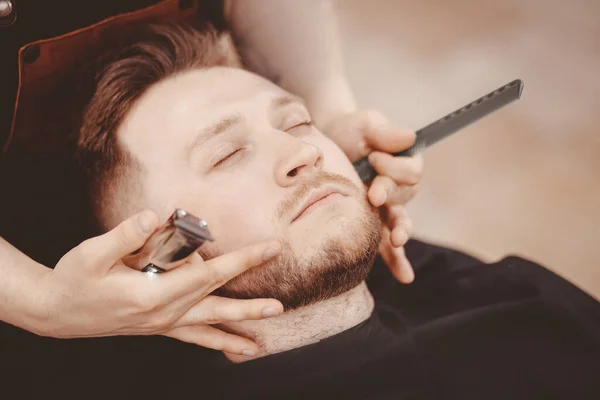 Man Barber borotválja szakáll ügyfél széken fodrászat — Stock Fotó