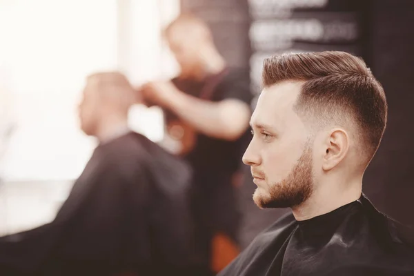 Баннер парикмахерской. Мужчина в парикмахерском кресле, парикмахер причесывает волосы . — стоковое фото