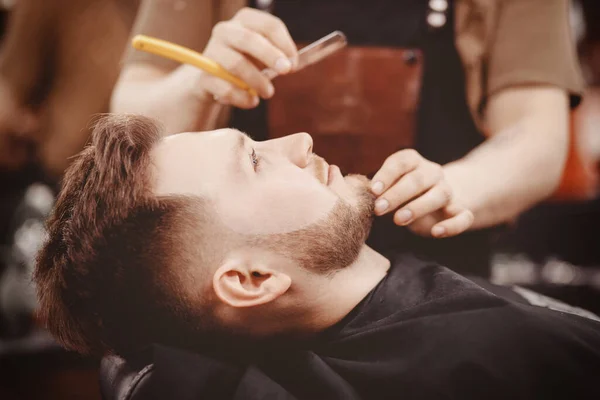 Homem Barbeiro barba barba de cliente na cadeira Barbershop — Fotografia de Stock