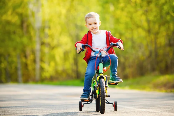 Menino feliz aprendeu a andar de bicicleta, segura volante e pedais. Desejo de conceito de sonho — Fotografia de Stock