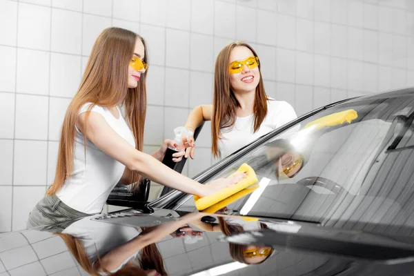 Dvě krásné ženy pracovnice mytí čelního skla houbou na mytí aut, leštění oken — Stock fotografie