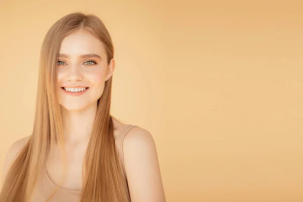 Piękny portret uśmiechnięta młoda kobieta z blond włosami, odizolowany na beżowym tle — Zdjęcie stockowe