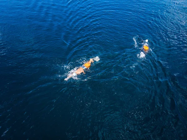 北极人在冷水中畅游冰洞，运动员穿着潮湿的衣服，蓝色的海上挂着橙色的浮标 — 图库照片