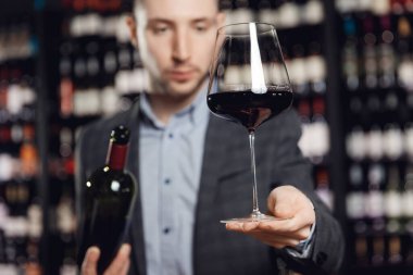 Sommelier restoranda kırmızı şarabı şişeden cam bardağa doldurur.