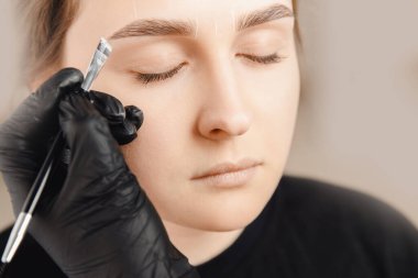 Düzeltme ve kaş rengi, usta kaş işaretleyen kadına fırça uyguluyor.