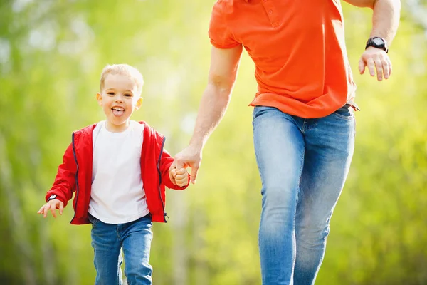 Feliz conceito de desporto familiar. Pai e filho correm juntos na estrada no parque de verão — Fotografia de Stock