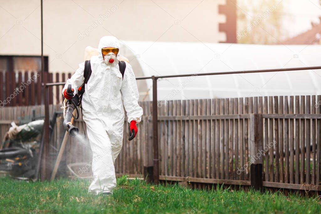 Disinfection of recreation parks from coronavirus virus, worker in protective suit with spray