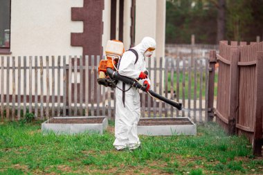 Koronavirüs virüsünden yayılan eğlence parklarının dezenfeksiyonu. Koruyucu giysili, spreyli işçi.