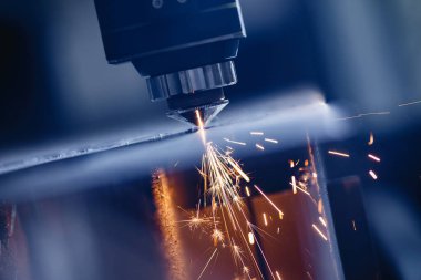 CNC gazı metal levha kesiyor, kıvılcımlar uçuşuyor. Mavi çelik rengi, modern endüstriyel teknoloji.